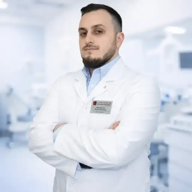 врач стоматолог Джабраилов Рахим Увайсович в белом халате на фоне клиники Имплант Эксперт