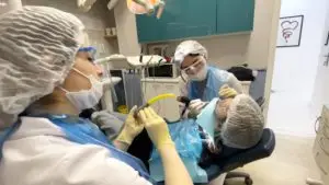 Стоматолог и ассистент проводят лечение зубов у пациента в современной клинике